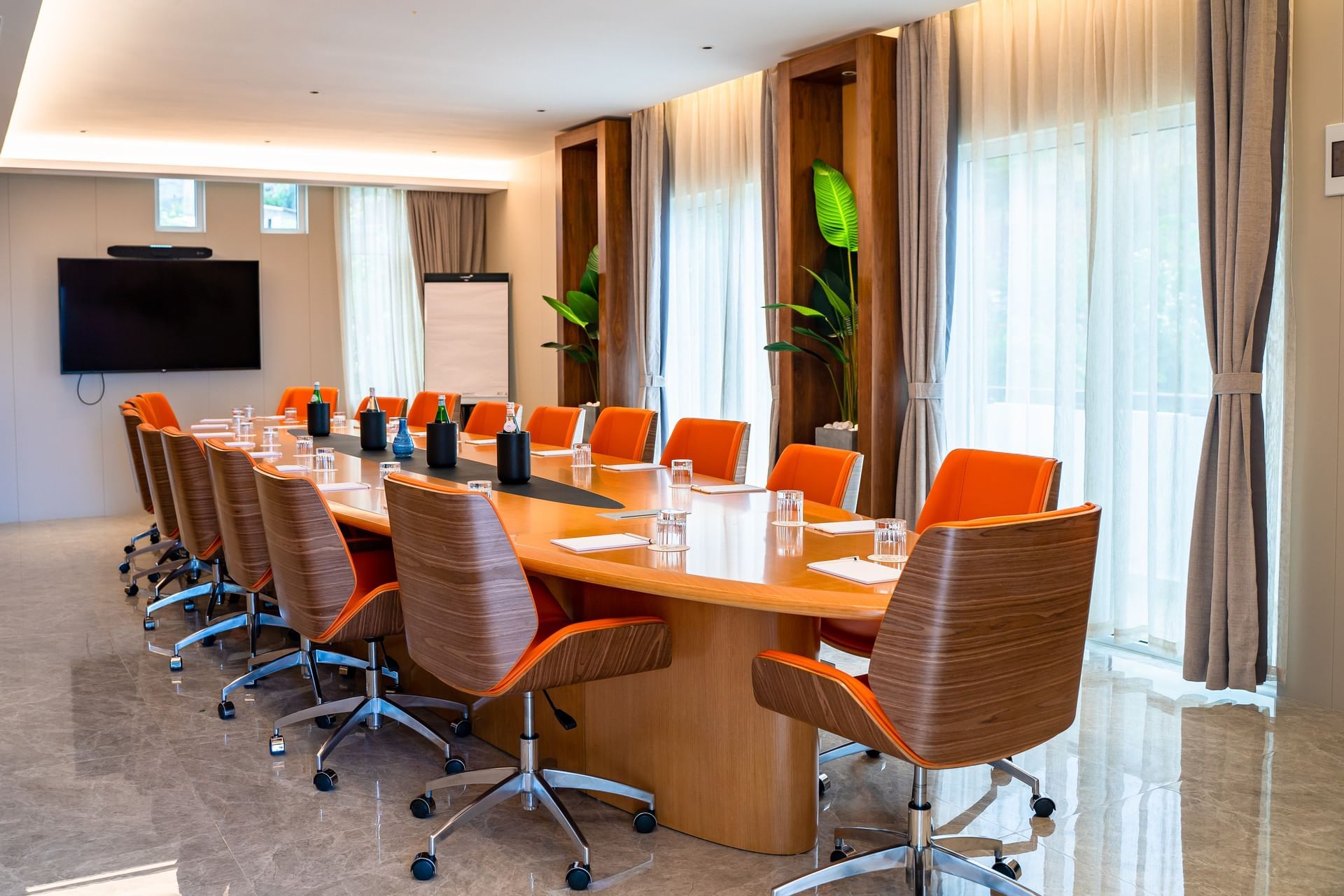 St. Barths boardroom met een grote ovale tafel, oranje stoelen gericht op tv bij de glazen ramen in Golden Rock Resort