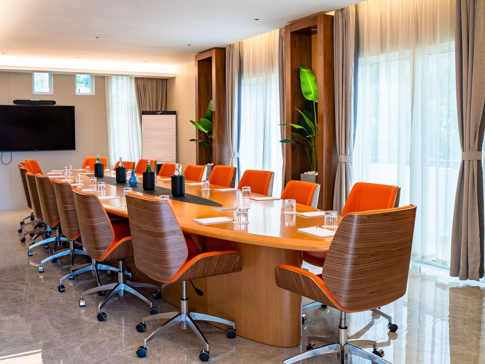 St. Barths boardroom met een grote ovale tafel, oranje stoelen gericht op tv bij de glazen ramen in Golden Rock Resort
