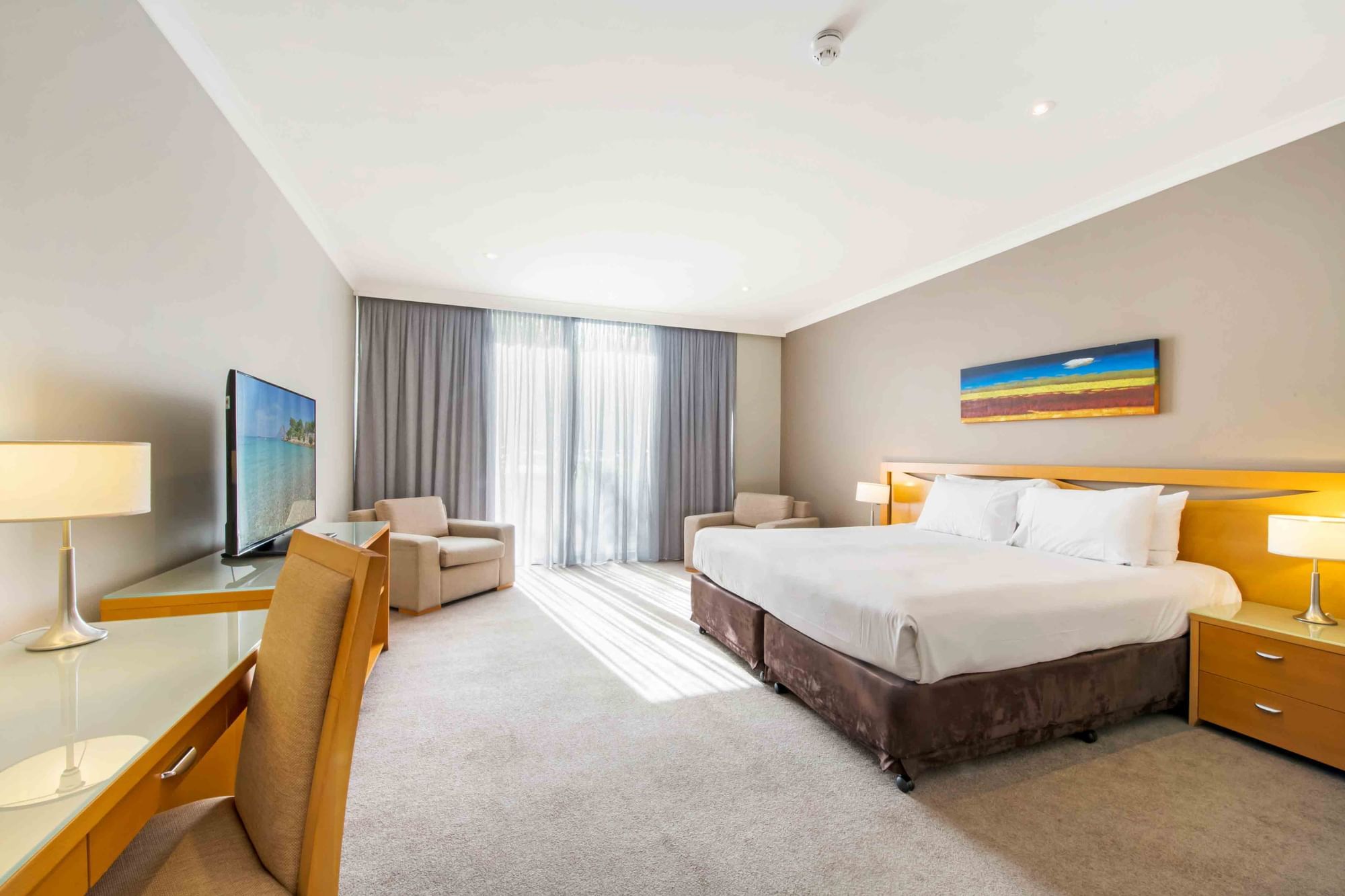 Standard Room - 1 King Bed with TV, chairs, and large window with curtains at Mercure Kooindah Waters