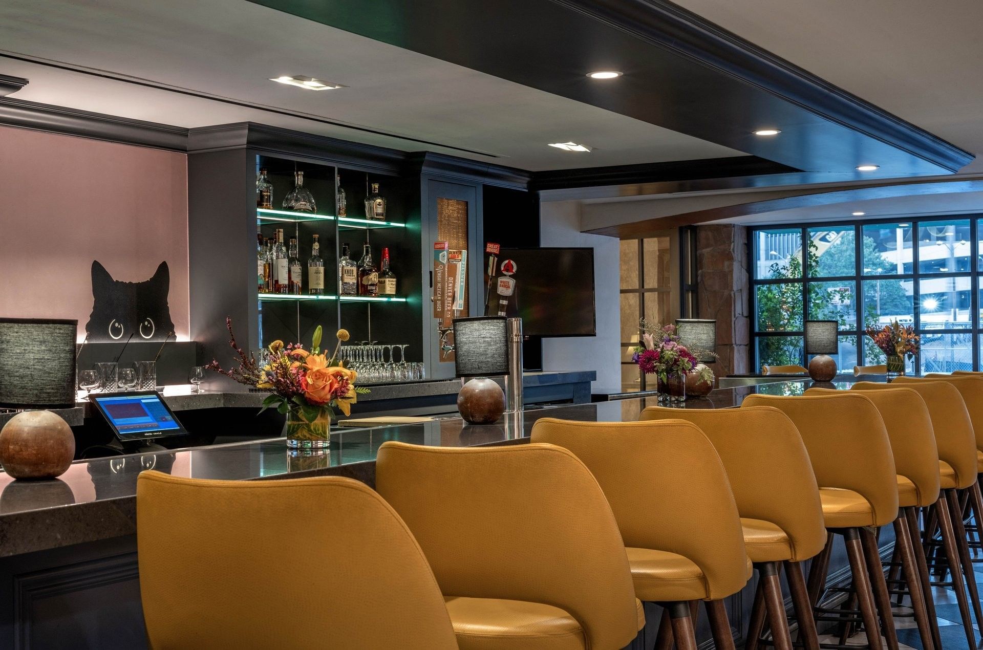 Stylish bar chairs by a long counter under recessed lights in Gattara Restaurant & Patio at Warwick Denver