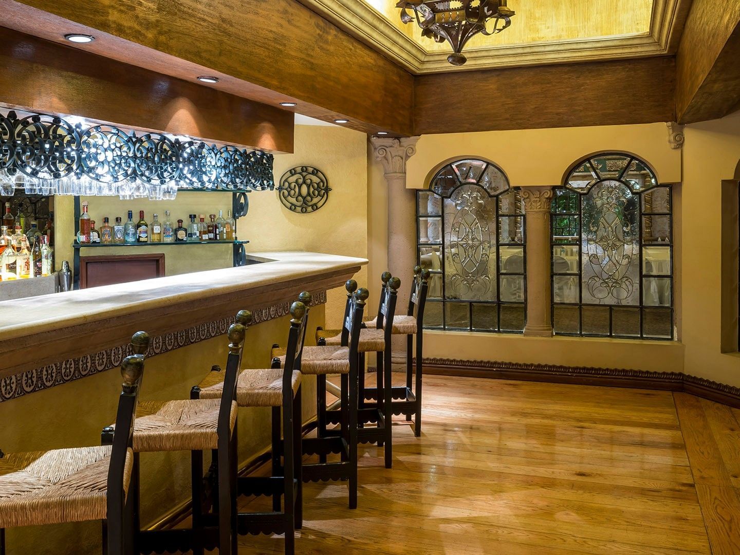 Elegant bar area with wooden floors, arched windows, and traditional Mexican decor at Quinta Real Aguascalientes