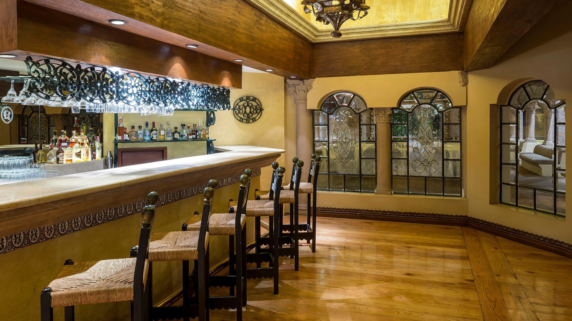 Elegant bar area with wooden floors, arched windows, and traditional Mexican decor at Quinta Real Aguascalientes
