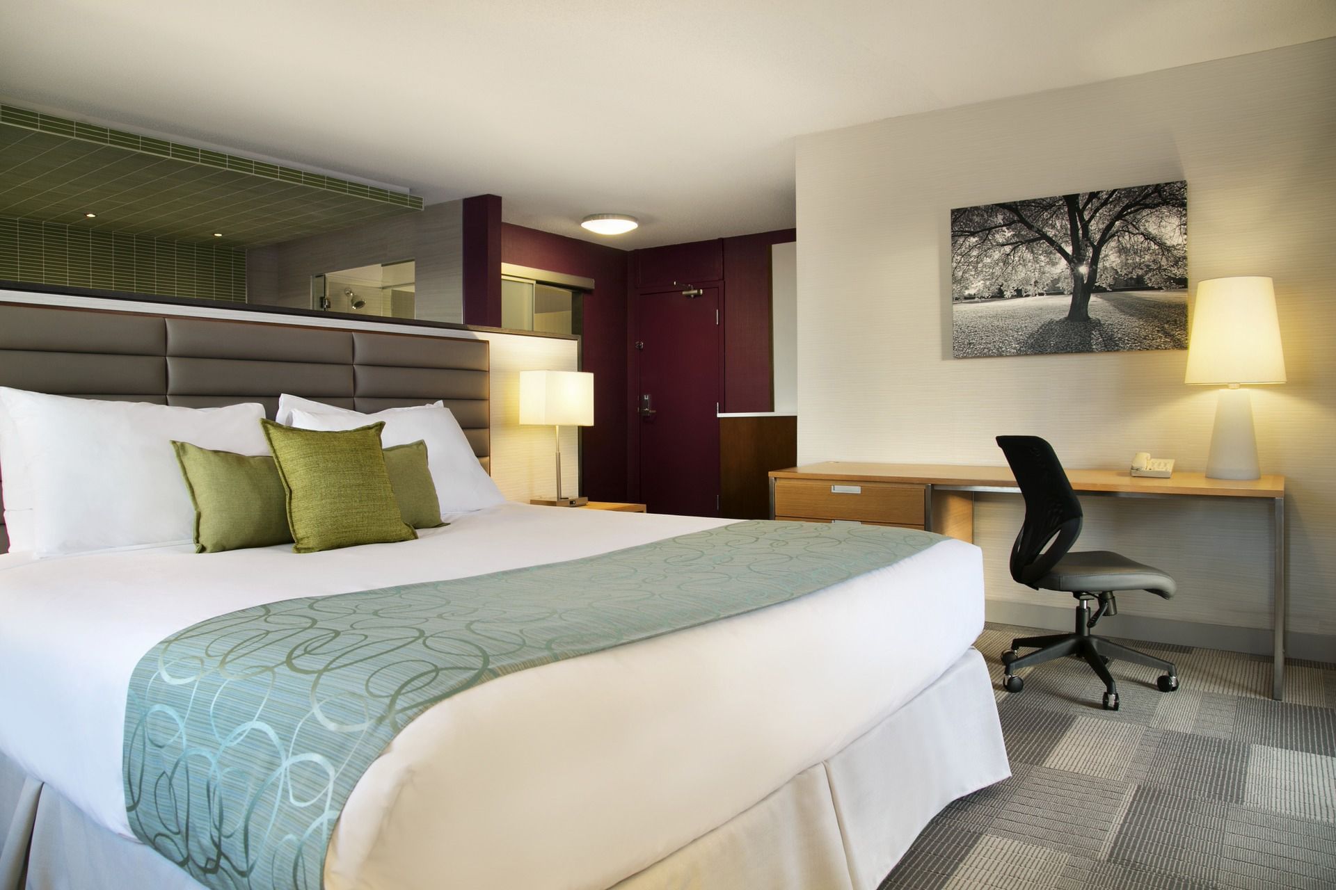 Bed in modern hotel room with desk