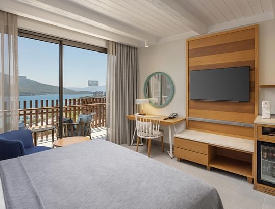 Family Room with balcony and sea view, featuring bed, desk, chair, TV, and mini-fridge.