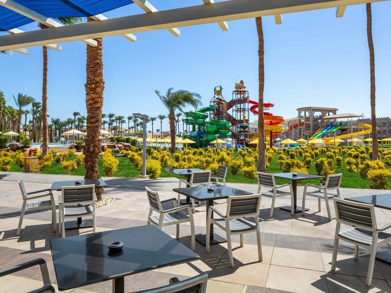 Outdoor seating area with tables and chairs near water slides at Beach Albatros Resort Hurghada Red Sea Governorate.