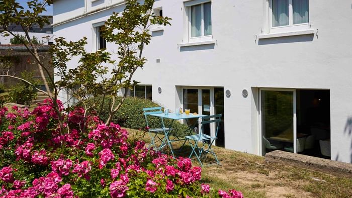 Table et chaises bleues devant l'Hôtel La Marébaudière avec fleurs roses