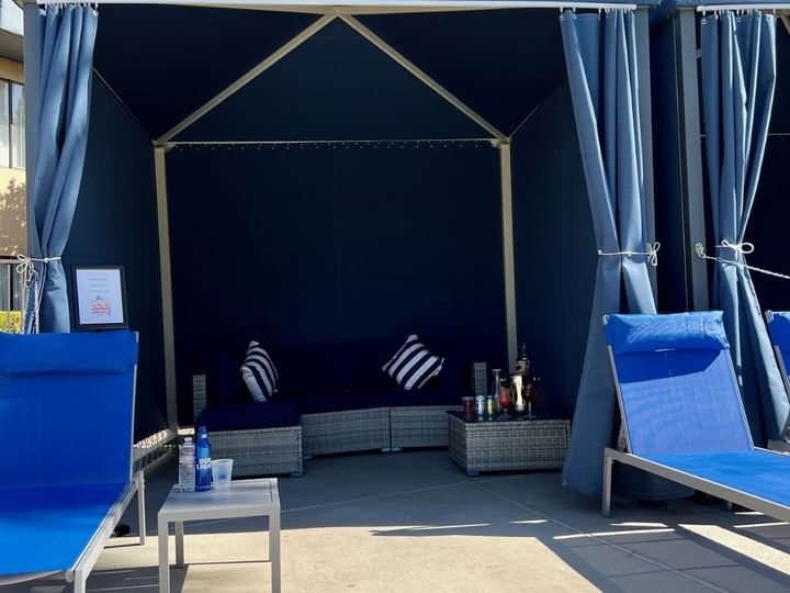 a cabana with blue lounge chairs and a table