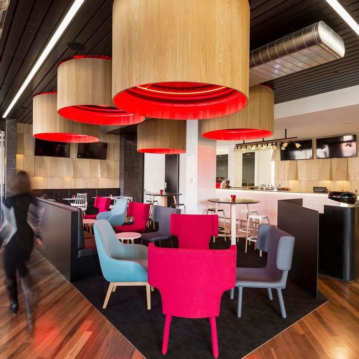 Guest walking through Level One Bar, surrounded by stylish seating and distinctive lighting at Ibis Adelaide