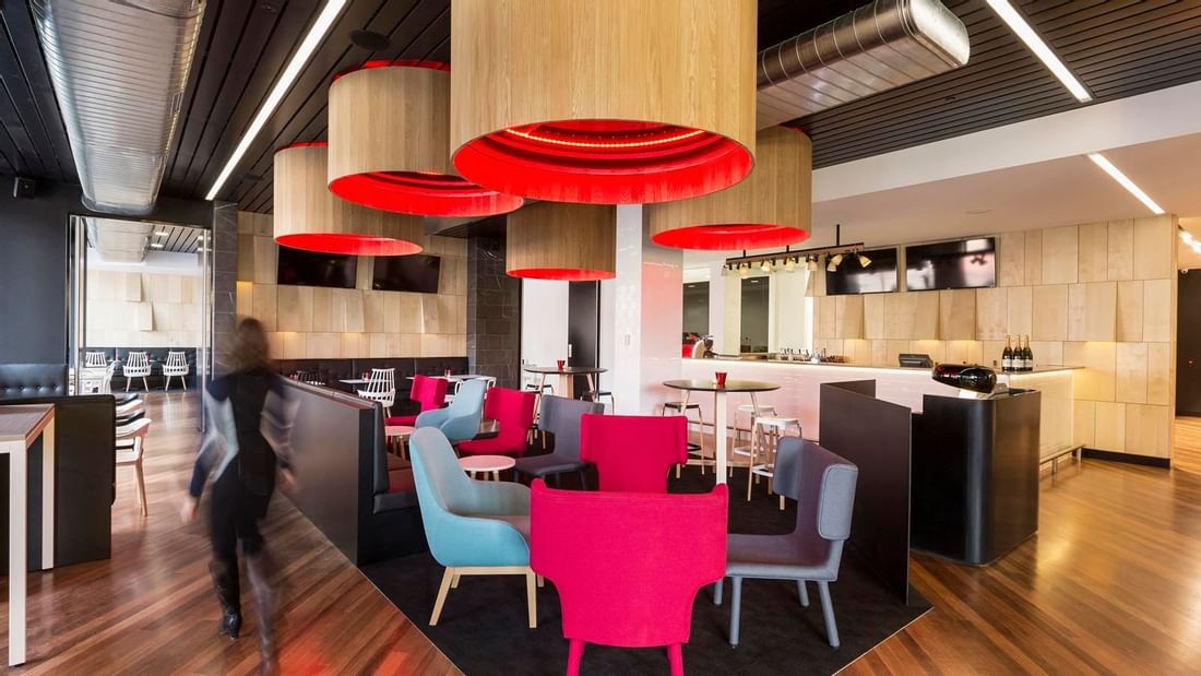Guest walking through Level One Bar, surrounded by stylish seating and distinctive lighting at Ibis Adelaide
