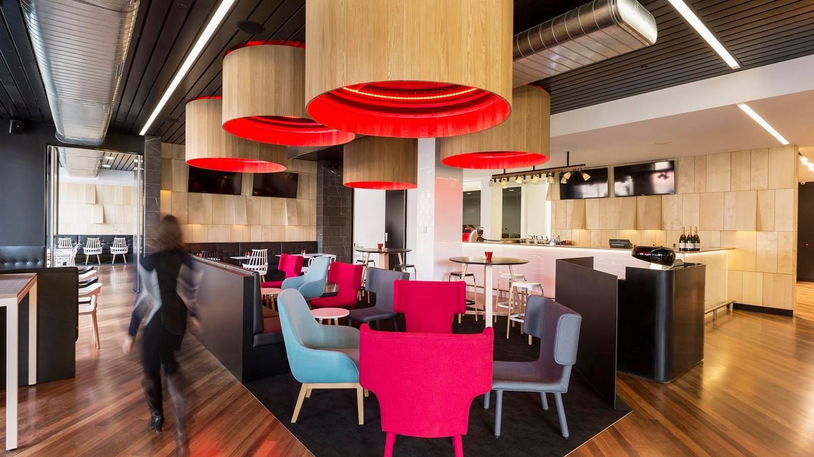 Guest walking through Level One Bar, surrounded by stylish seating and distinctive lighting at Ibis Adelaide