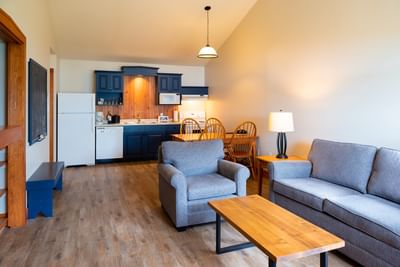 Grey seating by a wooden coffee table near a kitchen in Queen Cottage No Water View at Rodd Brudenell River Resort