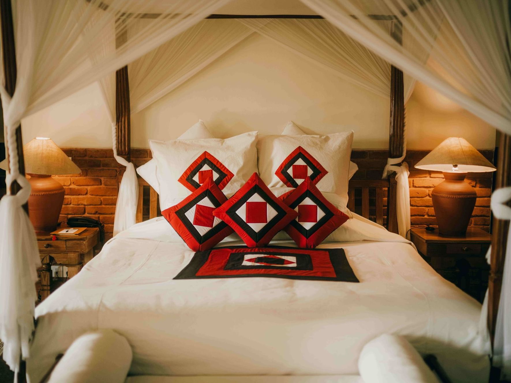 Four poster king bed with plush pillows in Heritage Deluxe Room at Dwarika's Hotel Kathmandu