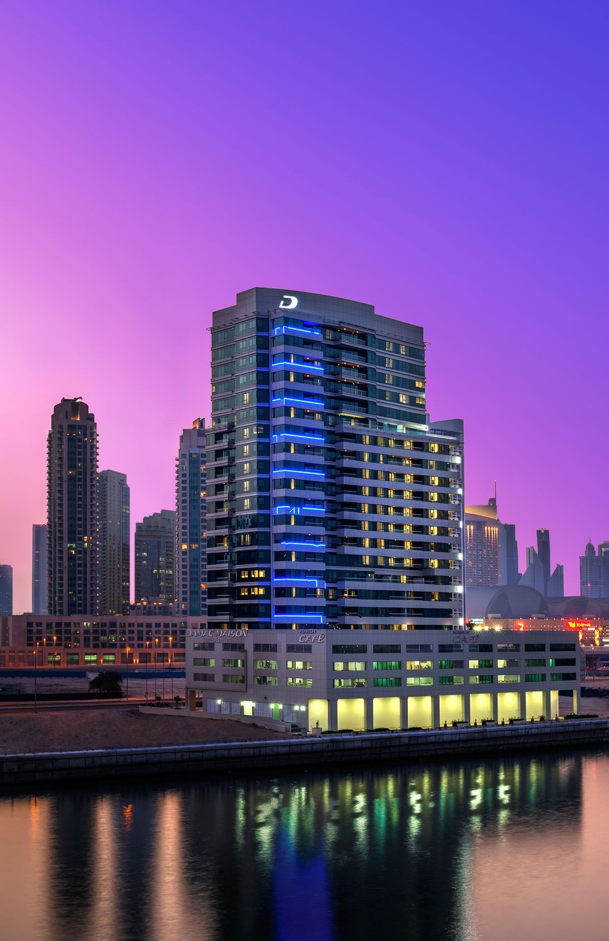 Elegant exterior of DAMAC Maison Canal Views in evening city lights featuring Premier 5-Star Hotel in Dubai
