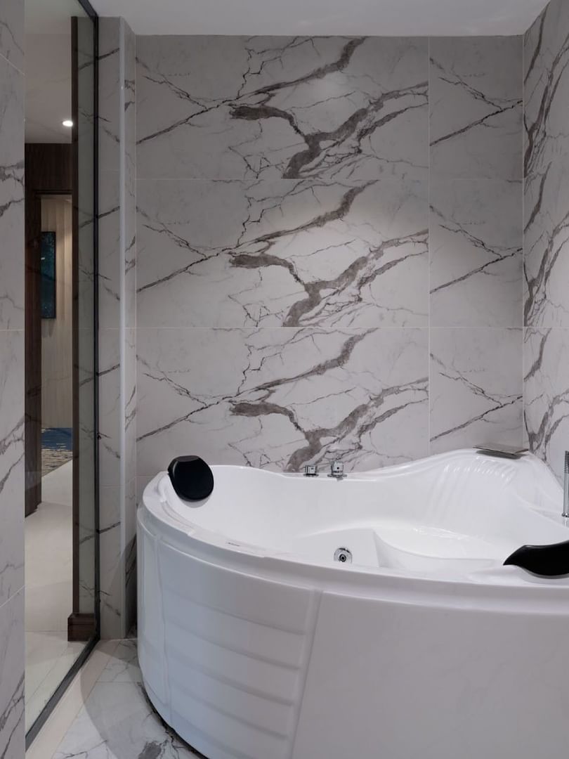 White whirlpool tub by marble walls in Royal Suite bathroom at the Warwick Al Taif Hotel