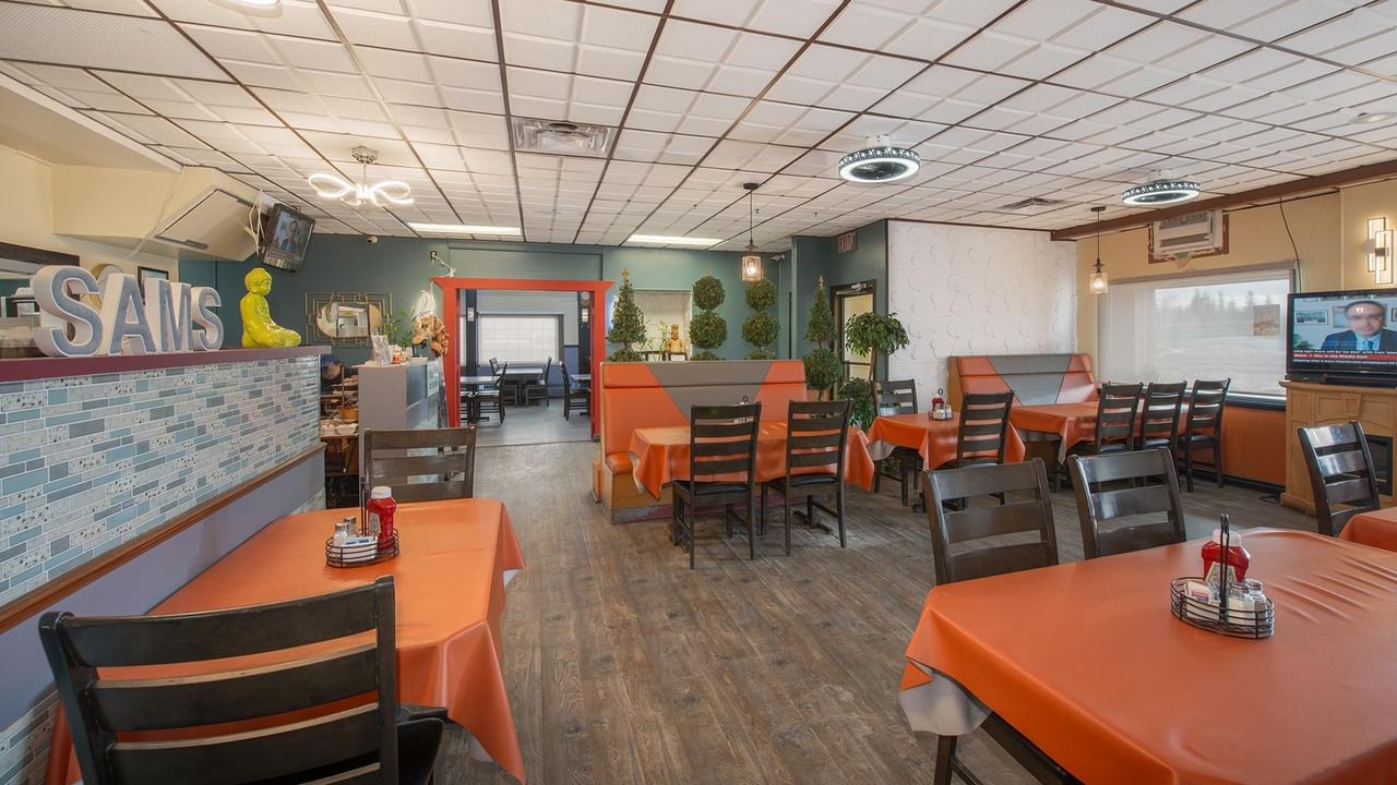 Restaurant with orange tablecloths and a TV.