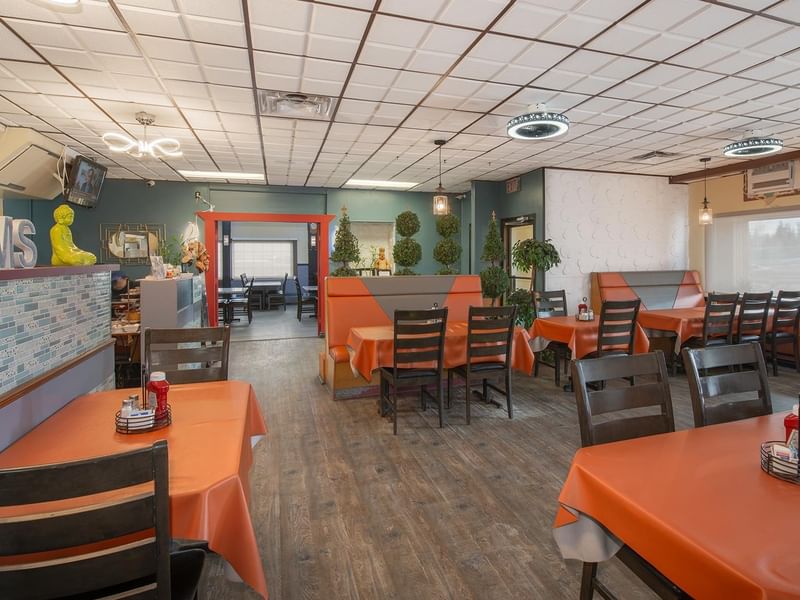 Restaurant with orange tablecloths and a TV.
