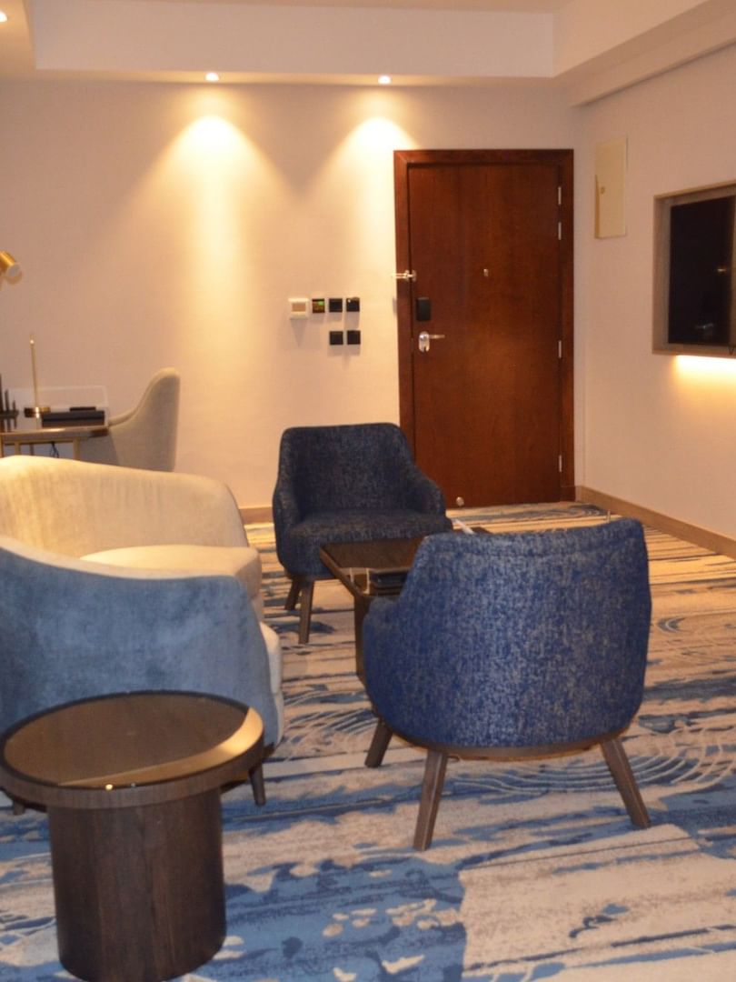 TV lounge with plush sofa beside doorway in Junior Suite at Warwick Jeddah Hotel & Spa