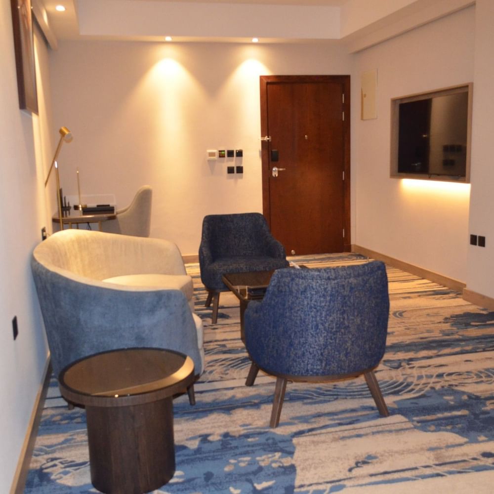TV lounge with plush sofa beside doorway in Junior Suite at Warwick Jeddah Hotel & Spa