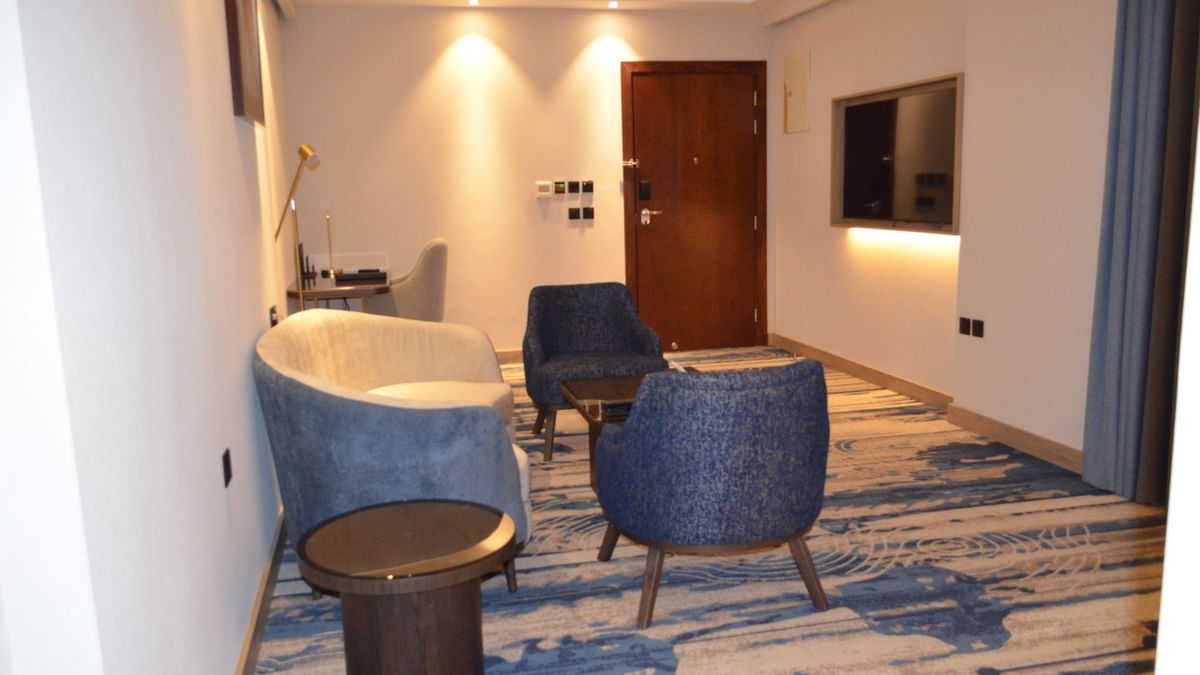TV lounge with plush sofa beside doorway in Junior Suite at Warwick Jeddah Hotel & Spa