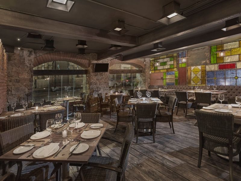 Dining tables set up with glassware in El Anafre Rojo restaurant at Gamma Hotels