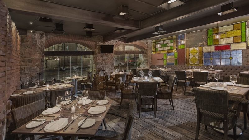 Dining tables set up with glassware in a restaurant at Gamma Puebla Senorial Centro