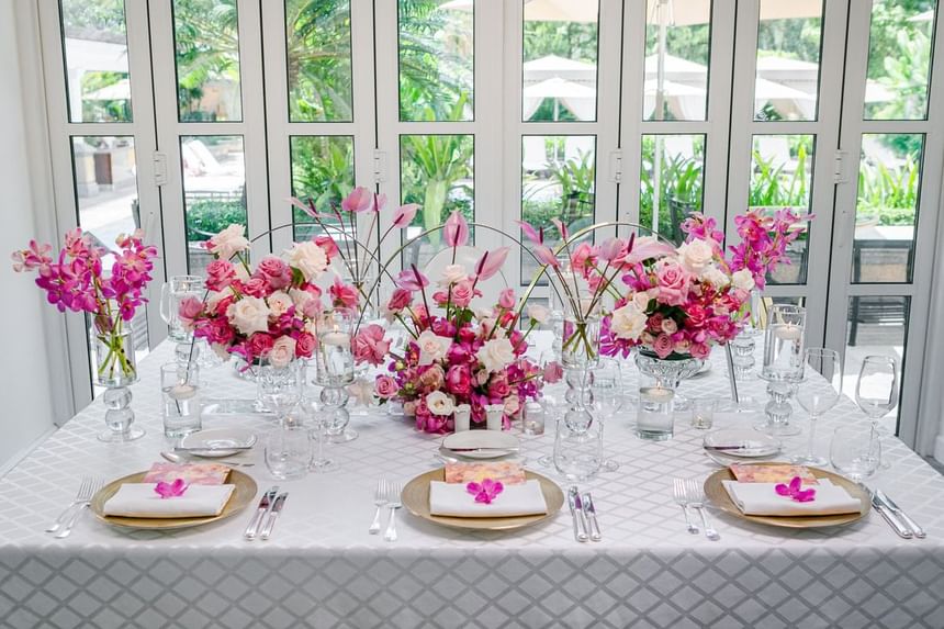 Elegant dining table set with pink floral centerpieces, gold and white place settings at Park Hyatt Saigon