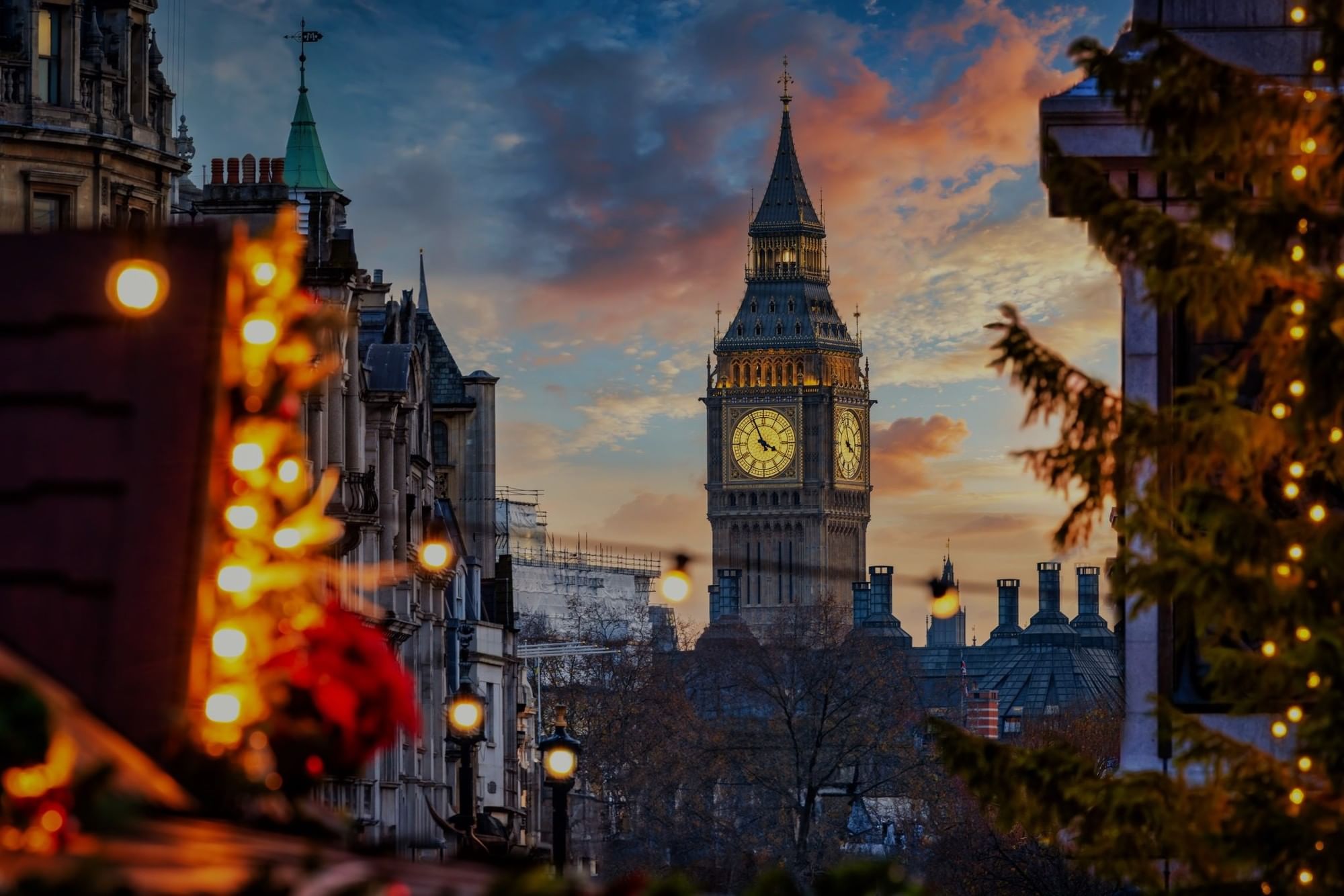 Big Ben clock tower illuminated at dusk with historic buildings and glowing street lights during winter time.