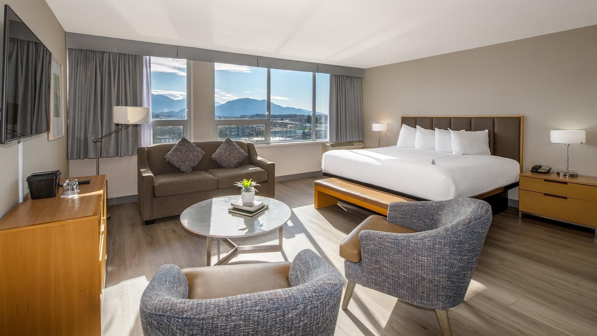 Hotel room with couch, coffee table, armchairs, bed, and view