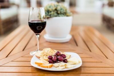 Glass of red wine with a cheese platter and grapes on a wooden table at Pavilion Hotel