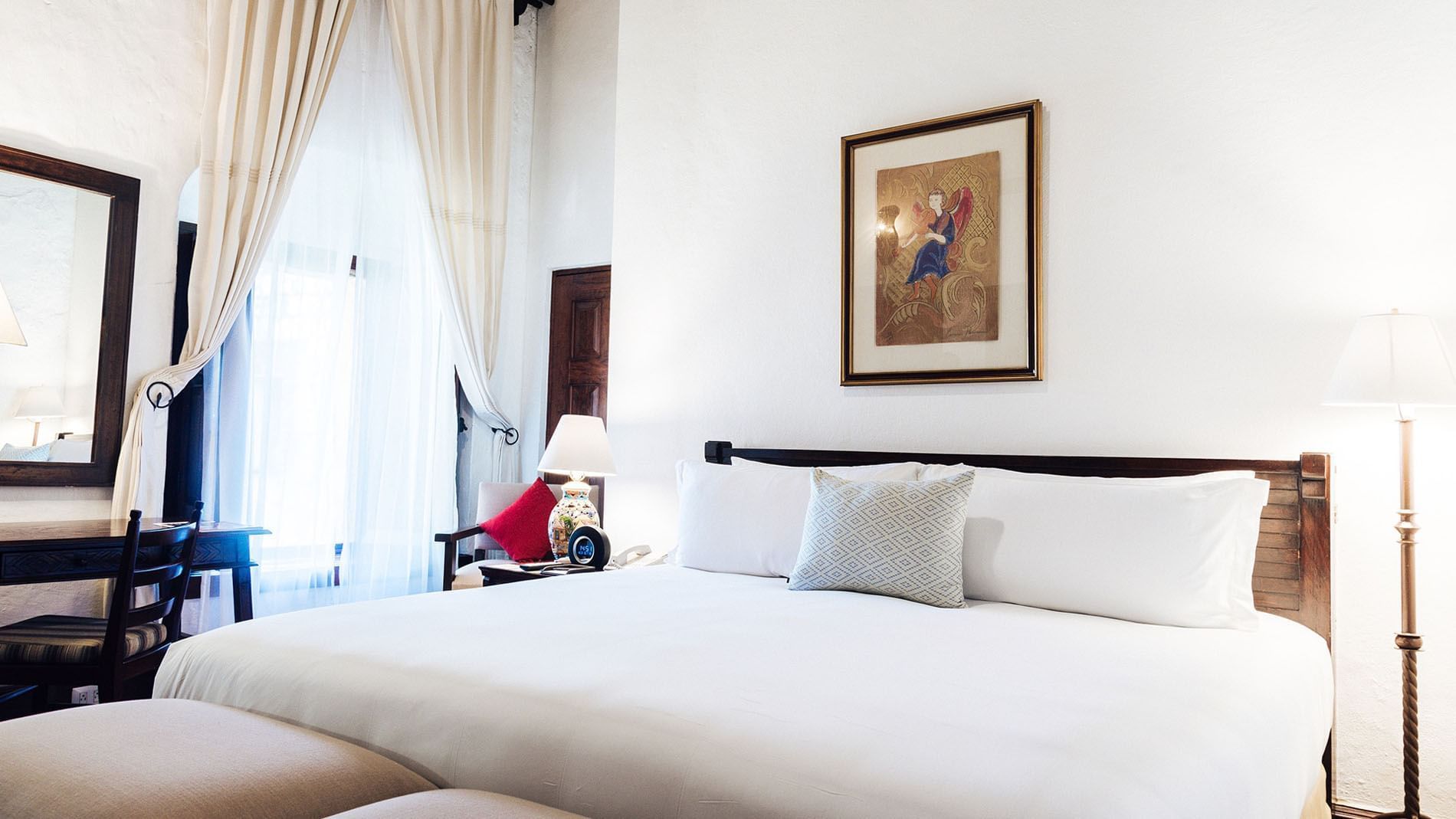 Work desk, ottoman, and nightstand by the cozy bed in the King Grand Class Suite at Quinta Real Oaxaca