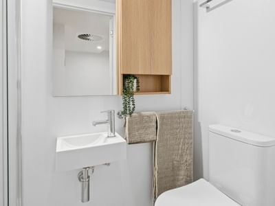 Modern bathroom with white toilet, sink, and wooden cabinet at UniLodge Brisbane City.