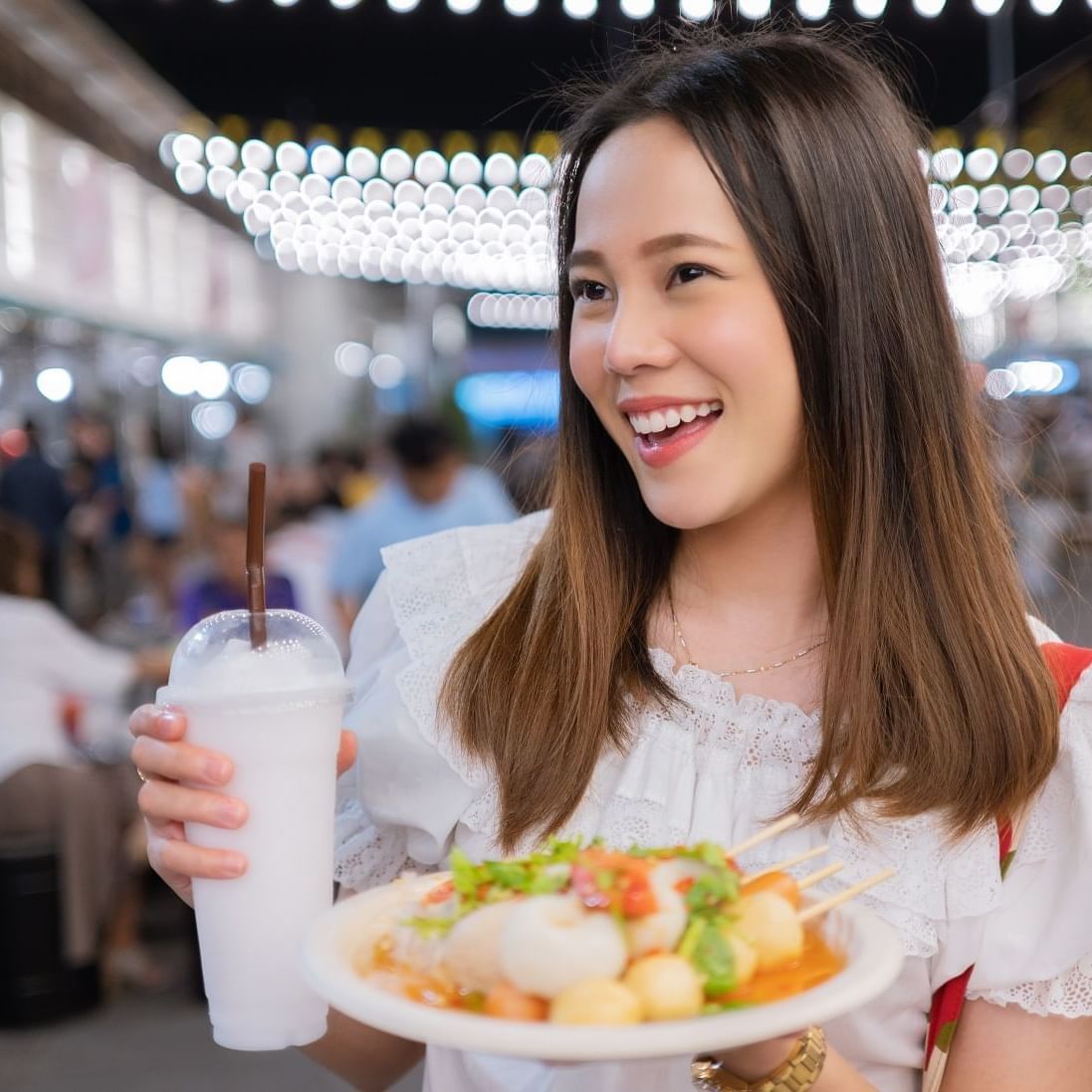 A woman holding food plate and a drink near Paradox Singapore