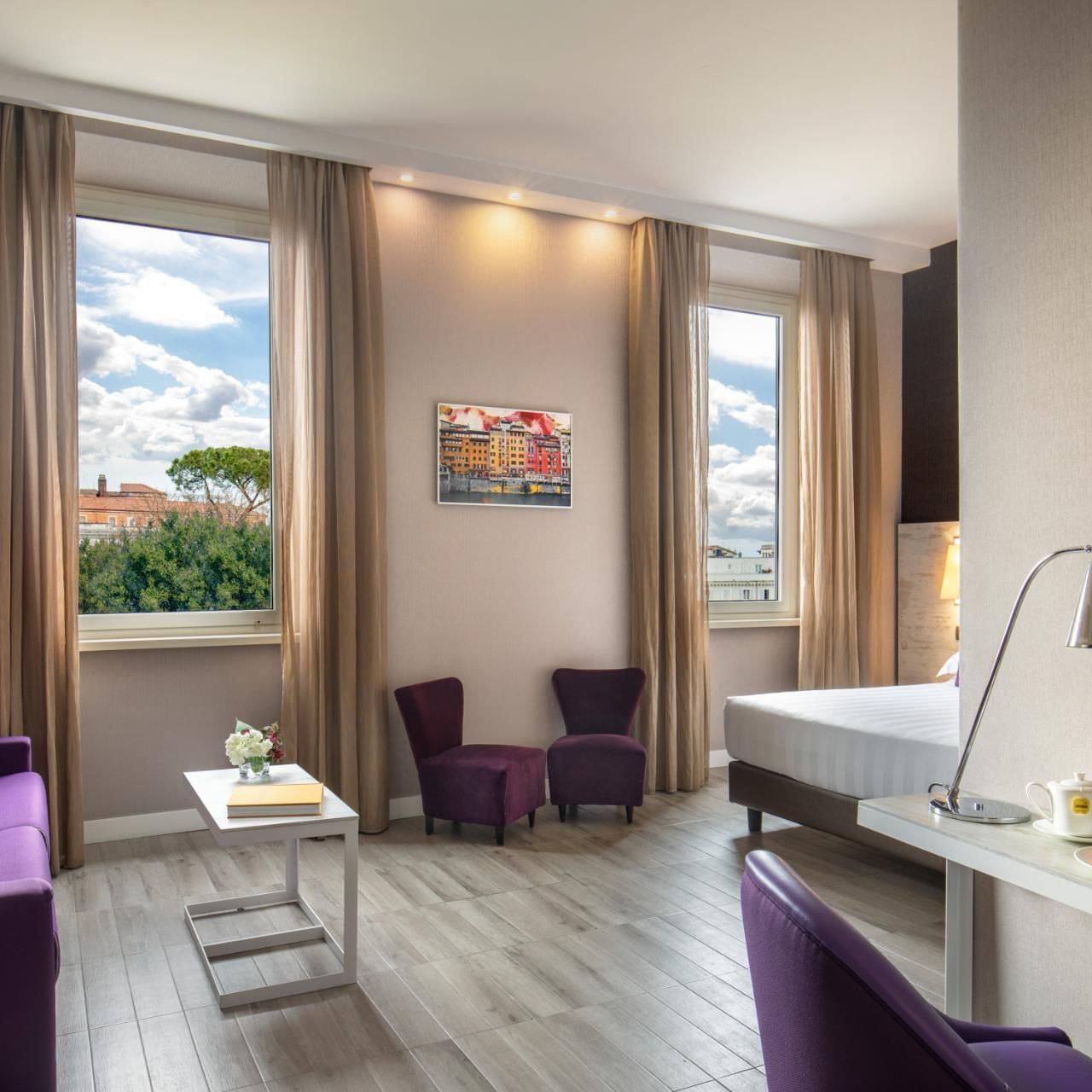 The Guardian room with purple seating, a modern desk, large windows, and outside views at The Guardian Hotel 