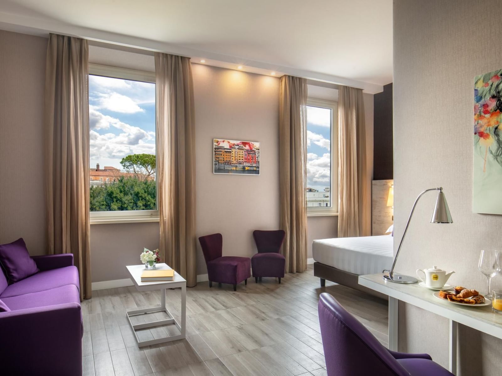 The Guardian room with purple seating, a modern desk, large windows, and outside views at The Guardian Hotel