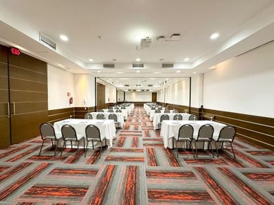 Asientos dispuestos en un suelo alfombrado del salón Ceibas en el Hotel San Fernando Plaza