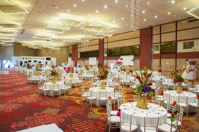 Round tables with floral centerpieces and white chairs set under sparkling ceiling panels at Megapolis Hotel Panama