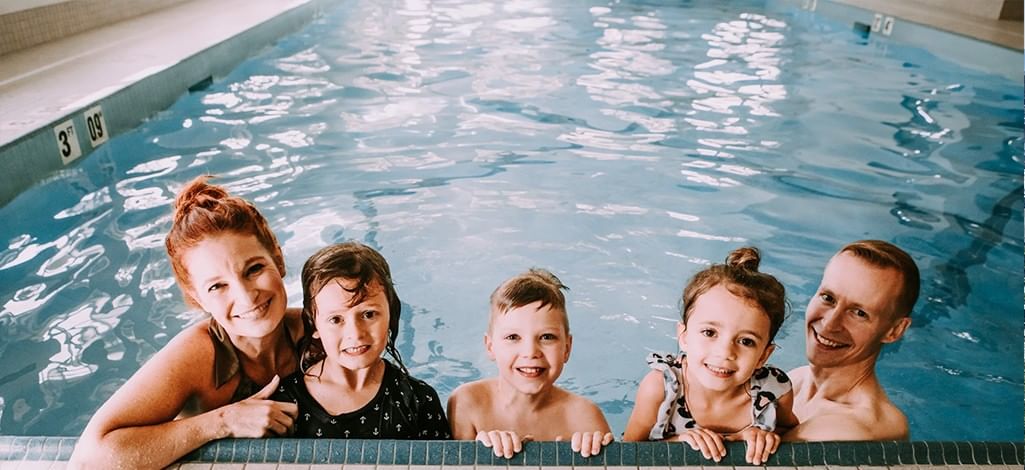 A family of five swims together in an indoor pool in Canmore on a rainy day.