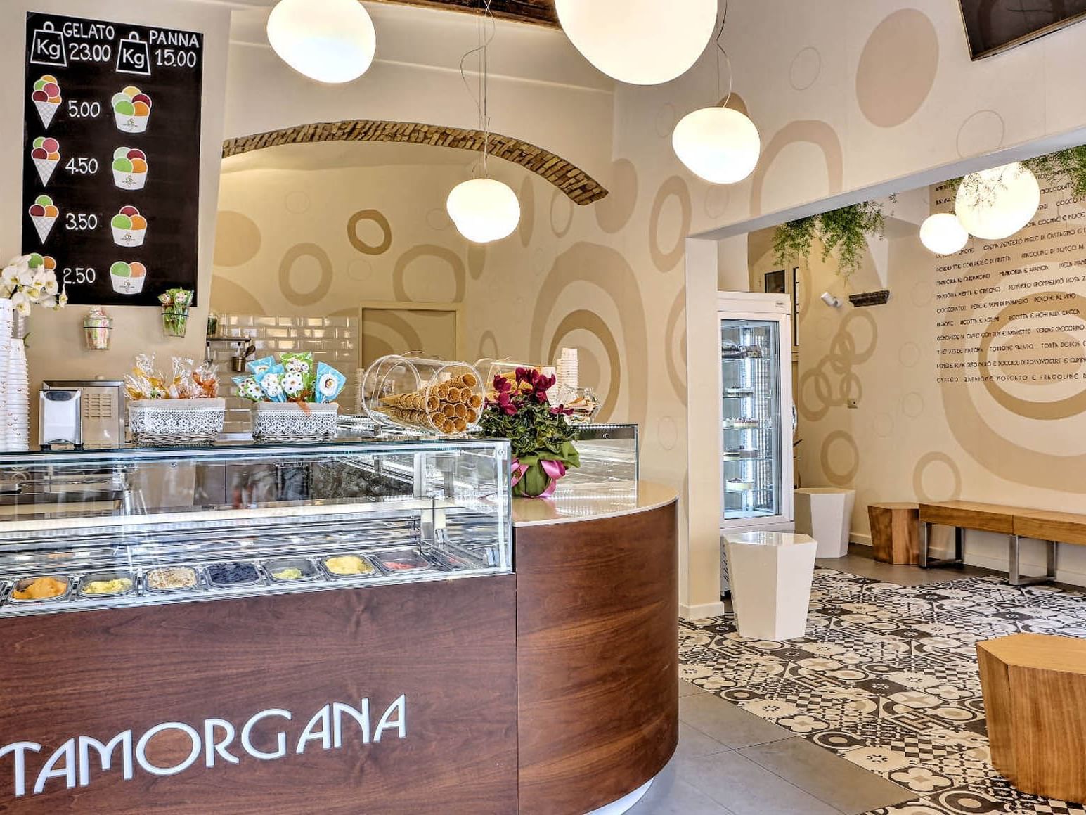 Tamorgana interior featuring a display case with colorful gelato flavors and a menu board overhead near The Glam Hotel