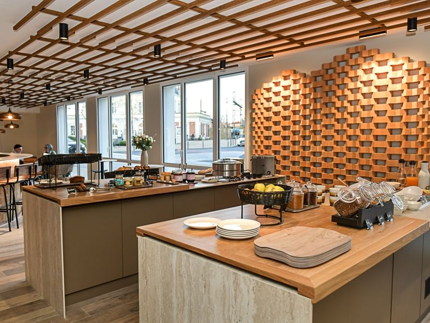 Buffet de petit-déjeuner élégant avec vaisselle et fruits sur un comptoir en bois au Hôtel Rivella.