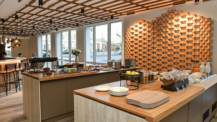 Buffet de petit-déjeuner élégant avec vaisselle et fruits sur un comptoir en bois au Hôtel Rivella.