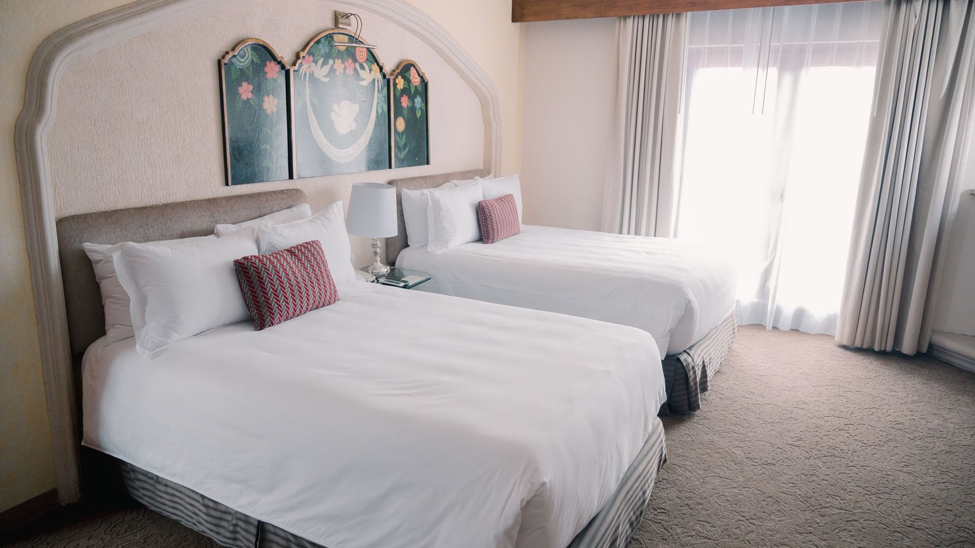Two made beds in 2 Double Master Suite with a window, carpet, and artwork on the wall at Quinta Real Zacatecas