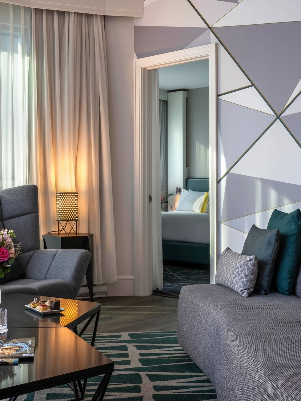 Living room with gray couches, modern decor, and a view of a bedroom at Warwick Le Crystal.