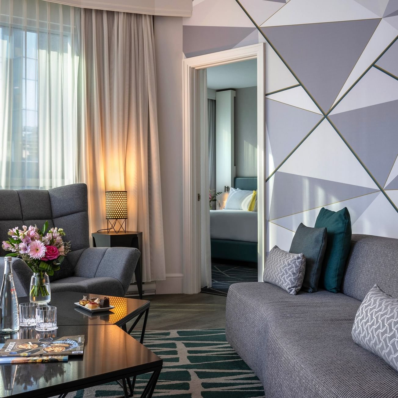 Salon avec des canapés gris, une décoration moderne et une vue sur une chambre à Warwick Le Crystal.