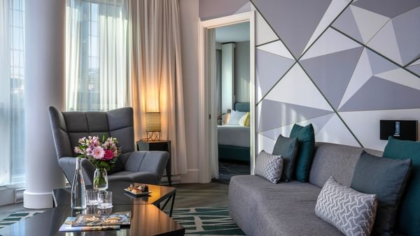 Living room with gray couches, modern decor, and a view of a bedroom at Warwick Le Crystal.