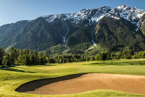 A golf course near Blackcomb Springs Suites with a scenic view of lush green