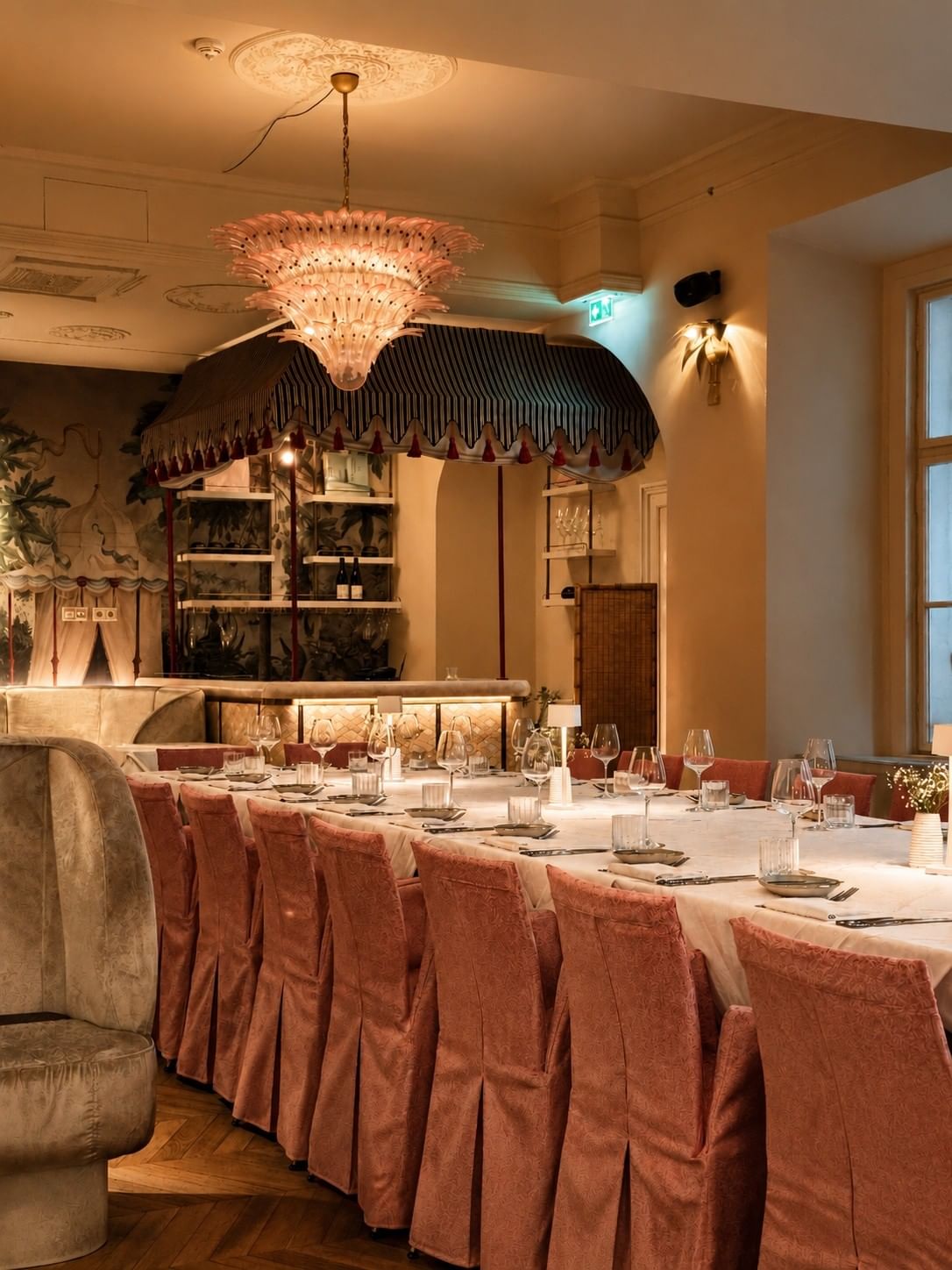 Eleganter Restaurantraum mit gedecktem Tisch, rosafarbenen Stühlen und Kronleuchter