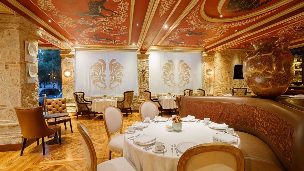 Tierra Mia restaurant featuring a painted ceiling, a large ceramic vase, and plush booth seating at Quinta Real Guadalajara