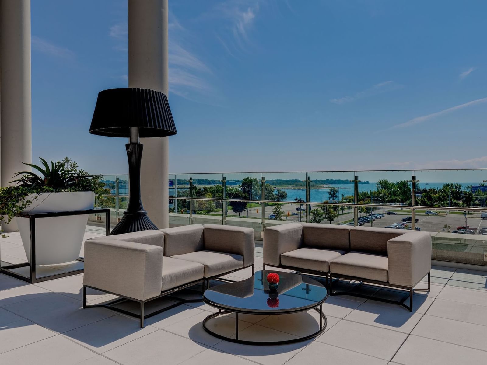 Modern outdoor terrace with sofa set, lamp, and waterfront view in Marina Terrace at Hotel X Toronto