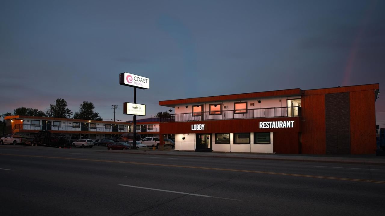 Exterior view of a Coast Dawson Creek Hotel at dusk, showing the lobby, restaurant and roadside hotel sign.