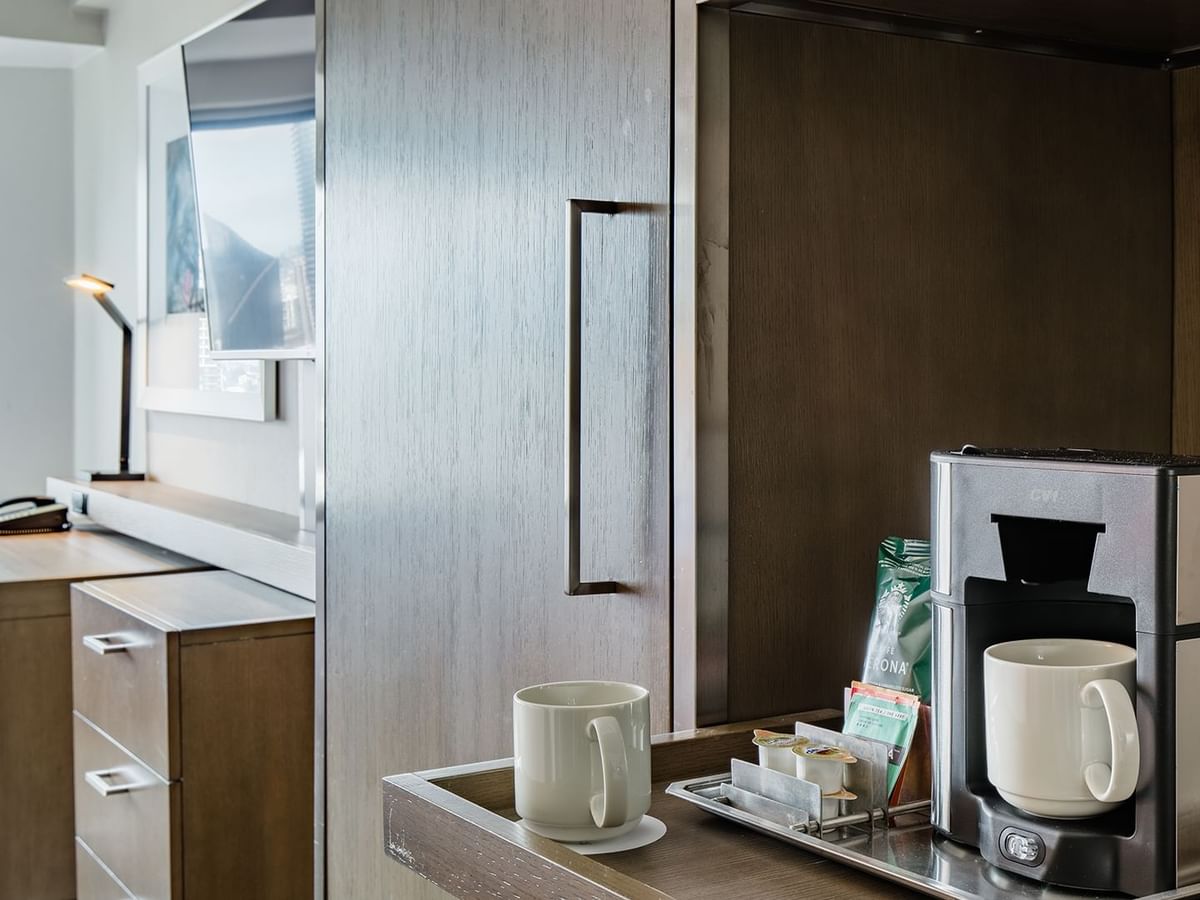 Accessible hotel guestroom with coffee machine, TV, and desk